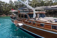 Aganlar Custom Motorsailer Gulet 2003 on serene turquoise waters, surrounded by lush greenery.