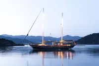 Aganlar Custom Motorsailer Gulet 2003, illuminated at dusk on calm waters, surrounded by hills.