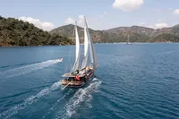 Aganlar Custom Motorsailer Gulet 2003 sailing on a serene blue sea with lush hills.