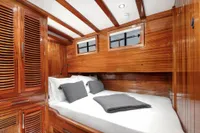 Luxurious wooden cabin interior of 2003 Aganlar Custom Motorsailer Gulet with cozy bed and windows.