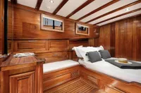 Luxurious wooden cabin interior of 2003 Aganlar Custom Motorsailer Gulet with cozy bed and elegant design.
