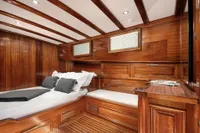 Luxurious wooden cabin interior of 2003 Aganlar Custom Motorsailer Gulet, featuring elegant design and cozy bedding.