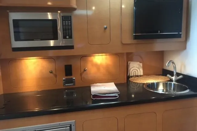 Yacht Photos Pics 2010 Rinker 400 Express Cruiser kitchen with microwave, sink, and sleek cabinetry.