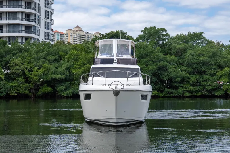  Yacht Photos Pics 2018 Ferretti Yachts 450 fly on calm water, surrounded by lush greenery and modern buildings.
