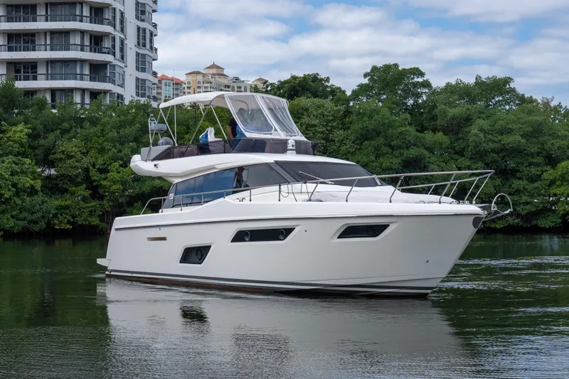  Yacht Photos Pics 2018 Ferretti Yachts 450 fly on calm water near modern buildings and lush greenery.