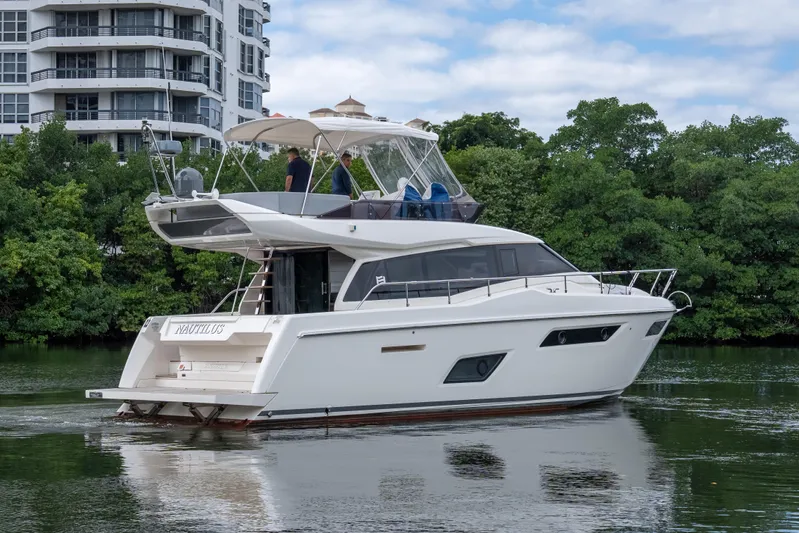  Yacht Photos Pics 2018 Ferretti Yachts 450 Fly cruising near modern buildings and lush greenery.