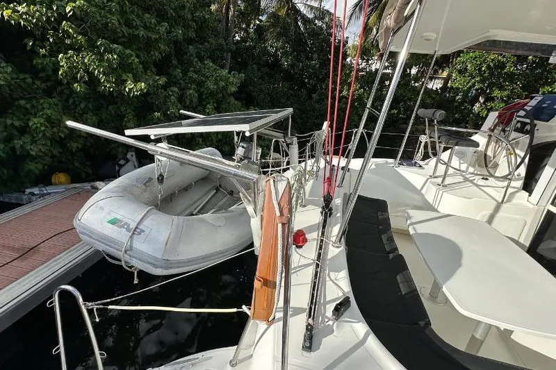 Nacrite Yacht Photos Pics 2018 Lagoon 380 catamaran with dinghy and solar panels docked near lush greenery.