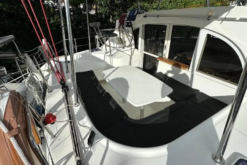Nacrite Yacht Photos Pics 2018 Lagoon 380 catamaran deck with seating and table, surrounded by lush greenery.