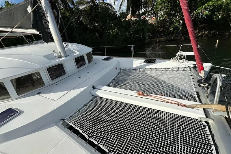 Nacrite Yacht Photos Pics 2018 Lagoon 380 catamaran deck with netting, docked near lush greenery.