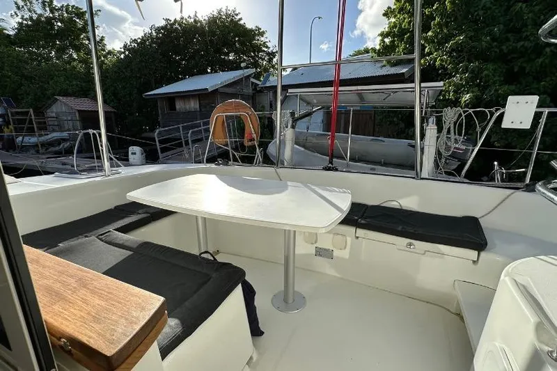 Nacrite Yacht Photos Pics 2018 Lagoon 380 catamaran cockpit with seating and table, surrounded by lush greenery.