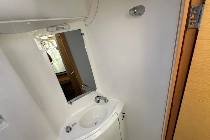 Nacrite Yacht Photos Pics Compact bathroom in 2018 Lagoon 380 catamaran with sink, mirror, and wooden door.