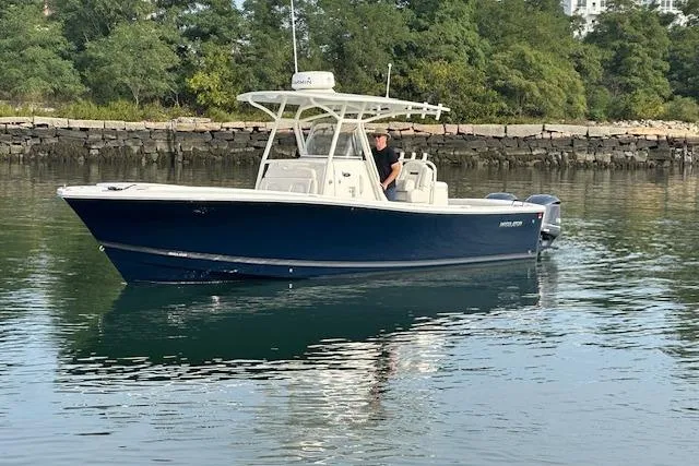 Resolute Yacht Photos Pics 2017 Regulator 31 boat on calm water near a rocky shoreline.