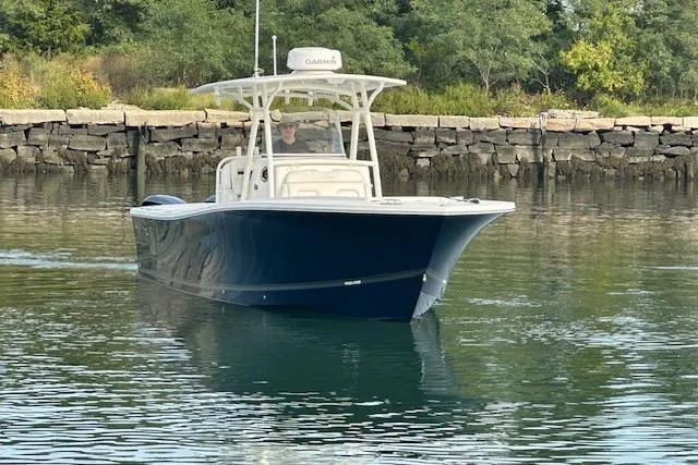Resolute Yacht Photos Pics 2017 Regulator 31 boat cruising on calm water near a rocky shoreline.
