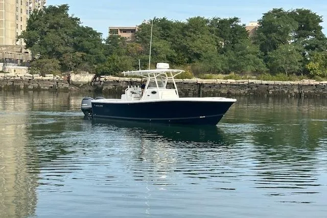 Resolute Yacht Photos Pics 2017 Regulator 31 boat on calm water near a rocky shoreline.