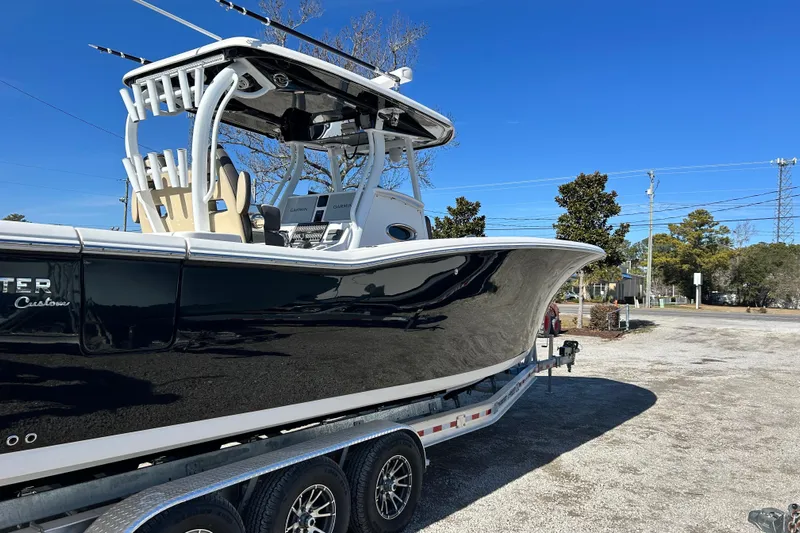  Yacht Photos Pics 2020 Tidewater 320 CC Adventure boat on trailer, sleek black hull, sunny day.