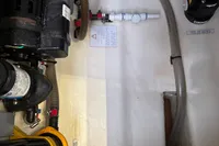 Engine compartment of 2019 Leopard 40 catamaran with visible hoses and warning labels.