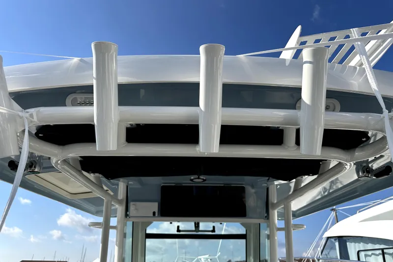  Yacht Photos Pics 2023 Boston Whaler OUTRAGE boat with rod holders under clear blue sky.