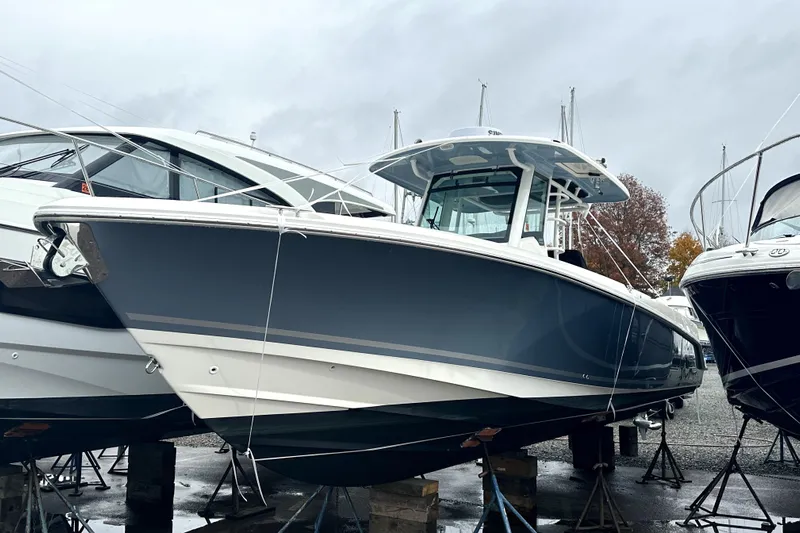  Yacht Photos Pics 2023 Boston Whaler OUTRAGE boat on stands, displayed outdoors on a cloudy day.