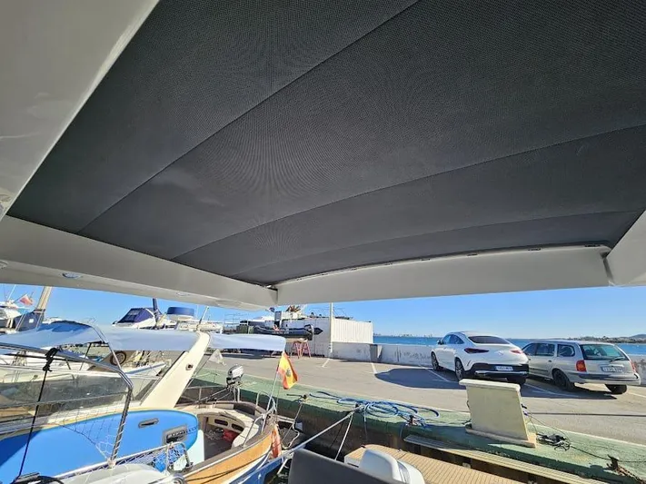  Yacht Photos Pics 2024 Sealine C390V yacht with sunroof, docked at marina, cars and sea in background.