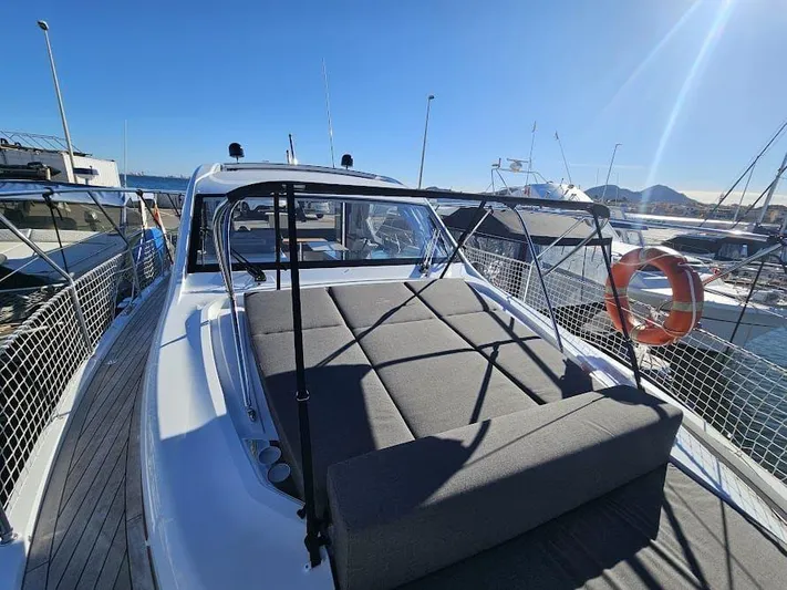  Yacht Photos Pics 2024 Sealine C390V yacht with sunbed on deck, docked at marina under clear blue sky.
