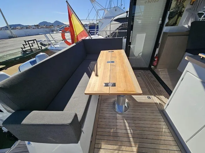  Yacht Photos Pics 2024 Sealine C390V yacht deck with wooden table and cushioned seating.