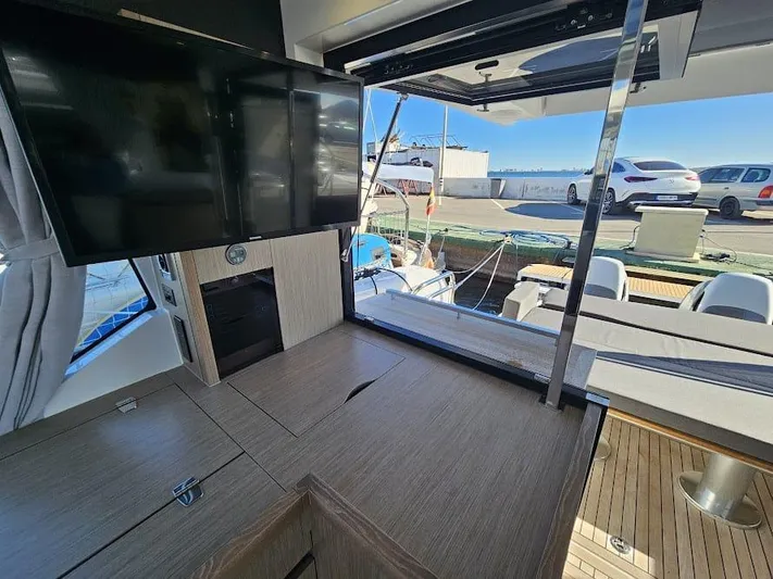  Yacht Photos Pics 2024 Sealine C390V yacht interior with TV, wooden cabinetry, and outdoor seating area.