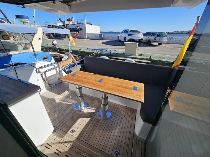  Yacht Photos Pics 2024 Sealine C390V yacht deck with wooden table and seating, docked at marina.