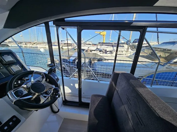  Yacht Photos Pics Interior view of 2024 Sealine C390V yacht, showcasing steering wheel and marina backdrop.
