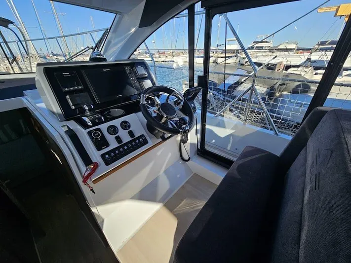  Yacht Photos Pics 2024 Sealine C390V helm with modern controls, steering wheel, and marina view.