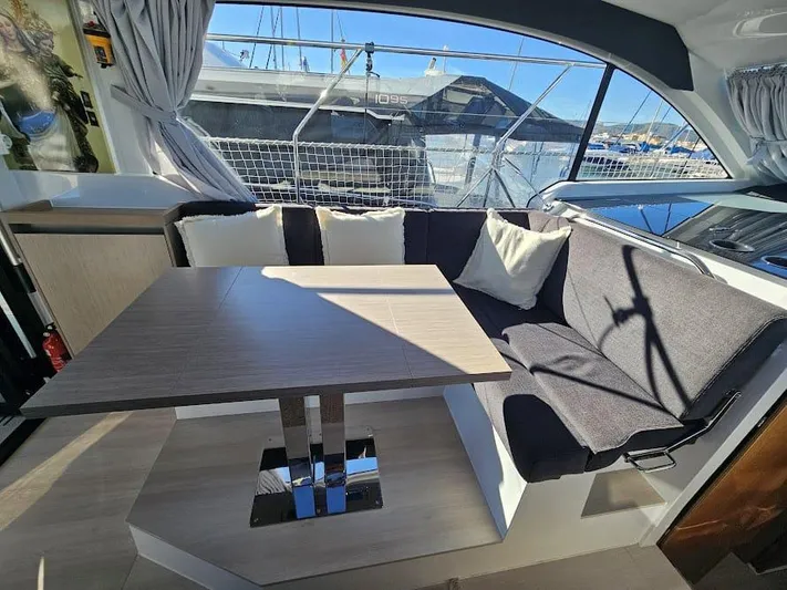  Yacht Photos Pics 2024 Sealine C390V yacht interior with cozy seating and dining table, marina view.