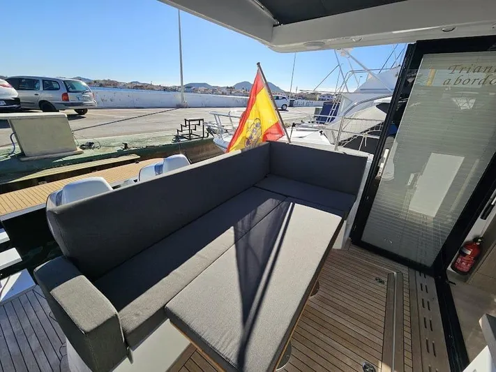  Yacht Photos Pics 2024 Sealine C390V yacht deck with seating, Spanish flag, and marina view.