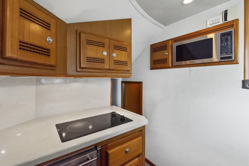 High Interest Yacht Photos Pics 2002 Cabo Convertible Painted yacht kitchen with stove, microwave, and wooden cabinets.