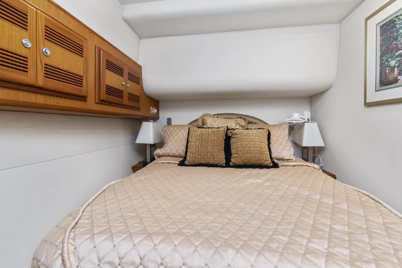 High Interest Yacht Photos Pics 2002 Cabo Convertible Painted boat interior bedroom with beige bedding and wooden cabinets.