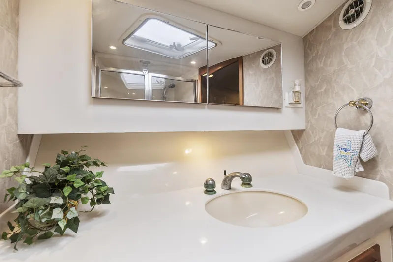 High Interest Yacht Photos Pics 2002 Cabo Convertible Painted boat bathroom with sink, mirror, and plant.