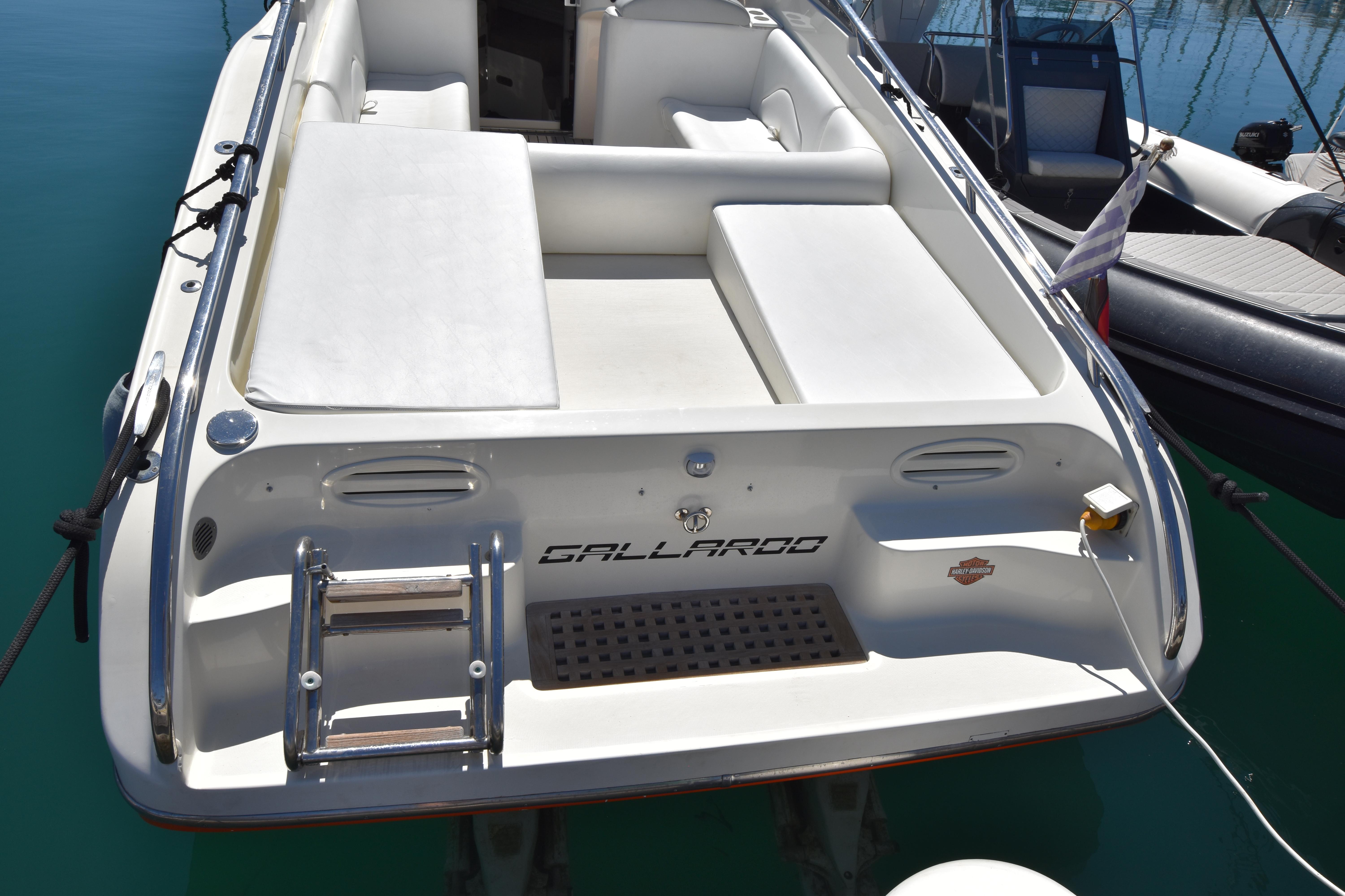 Rear view of a 2003 Performance 907 boat docked, featuring white seating and a swim ladder.