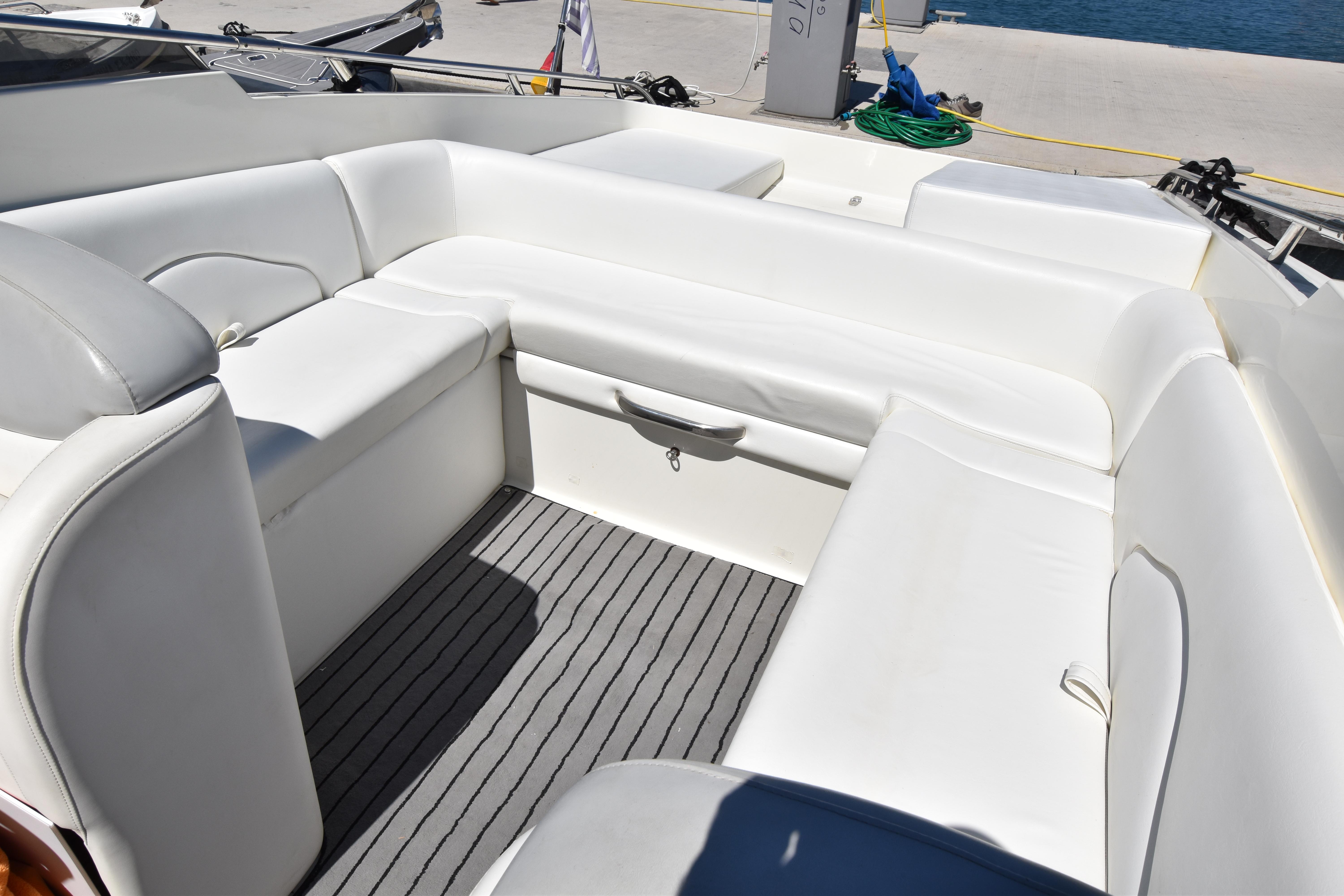 Luxurious white seating area on a 2003 Performance 907 boat, docked by the water.