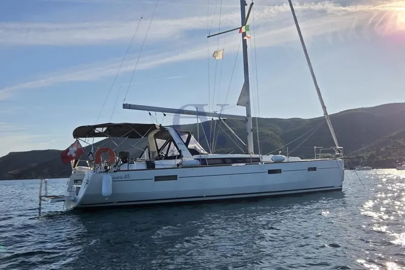 A Yacht Photos Pics 2018 Beneteau Oceanis 45 sailboat anchored in scenic waters, with mountainous backdrop.