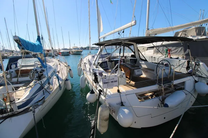 A Yacht Photos Pics 2018 Beneteau Oceanis 45 sailboat docked in marina, surrounded by other boats.