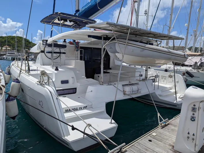 Mango IV Yacht Photos Pics 2017 Lagoon 42 catamaran docked at marina, featuring solar panels and dinghy.