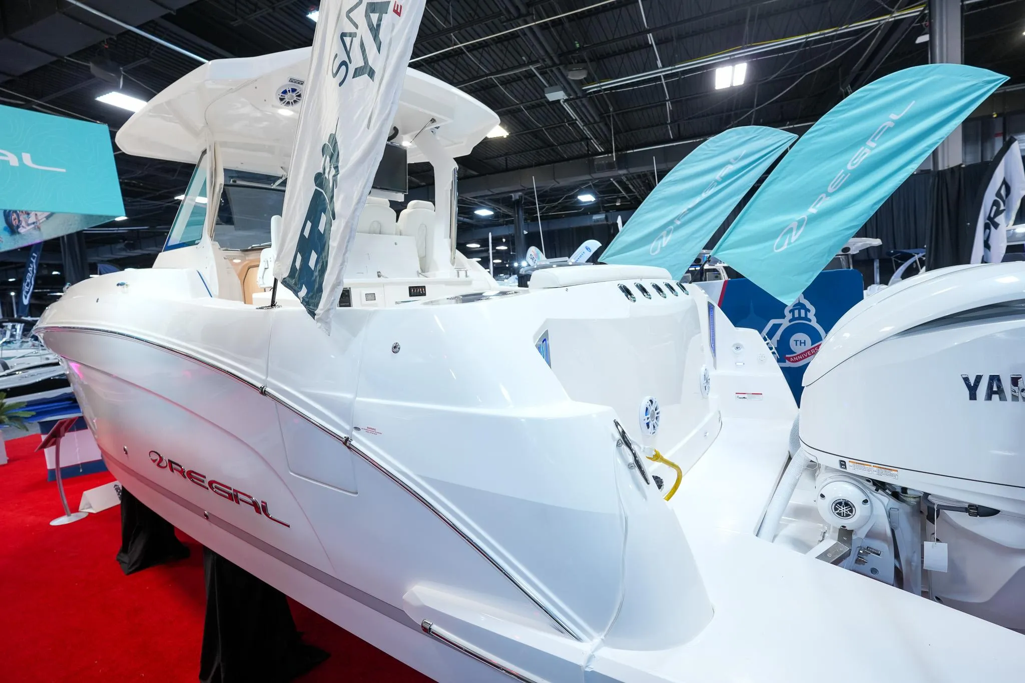 2025 Regal 33 SAV boat displayed indoors with vibrant red carpet and promotional banners.