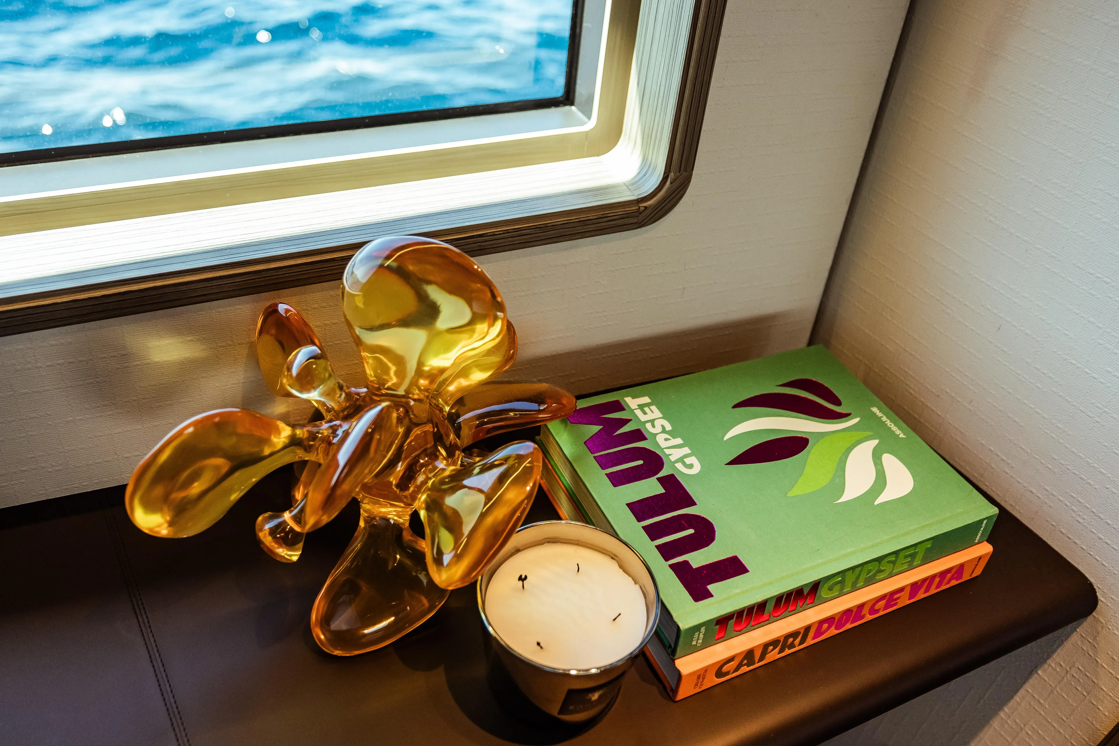 Decorative sculpture, books, and candle on Custom Line Navetta 30 yacht, 2022, with ocean view.