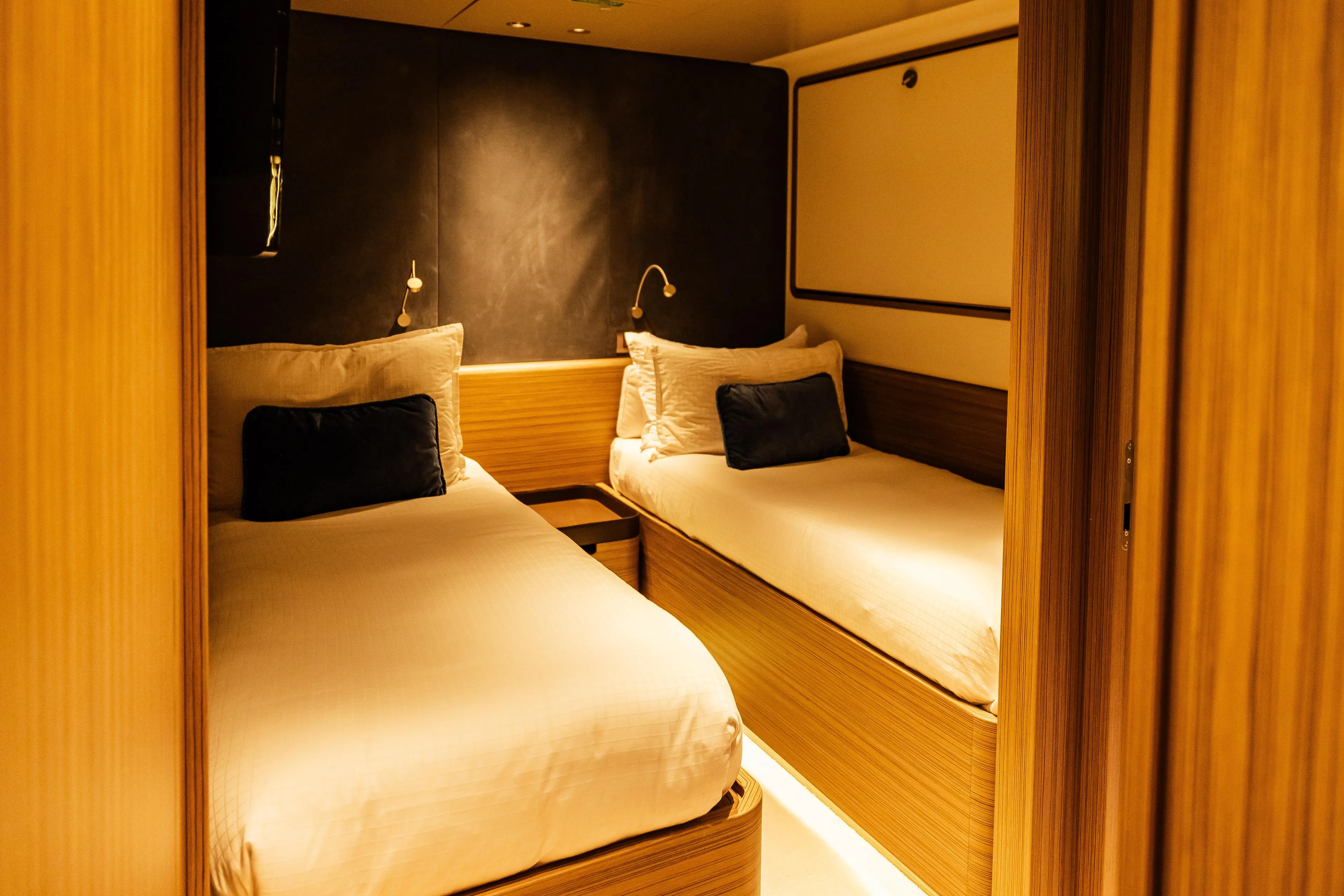 Luxurious twin cabin on 2022 Custom Line Navetta 30 yacht, featuring elegant wood finishes.