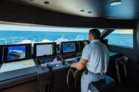 Man navigating Custom Line Navetta 30 yacht, 2022 model, with advanced control panels at sea.
