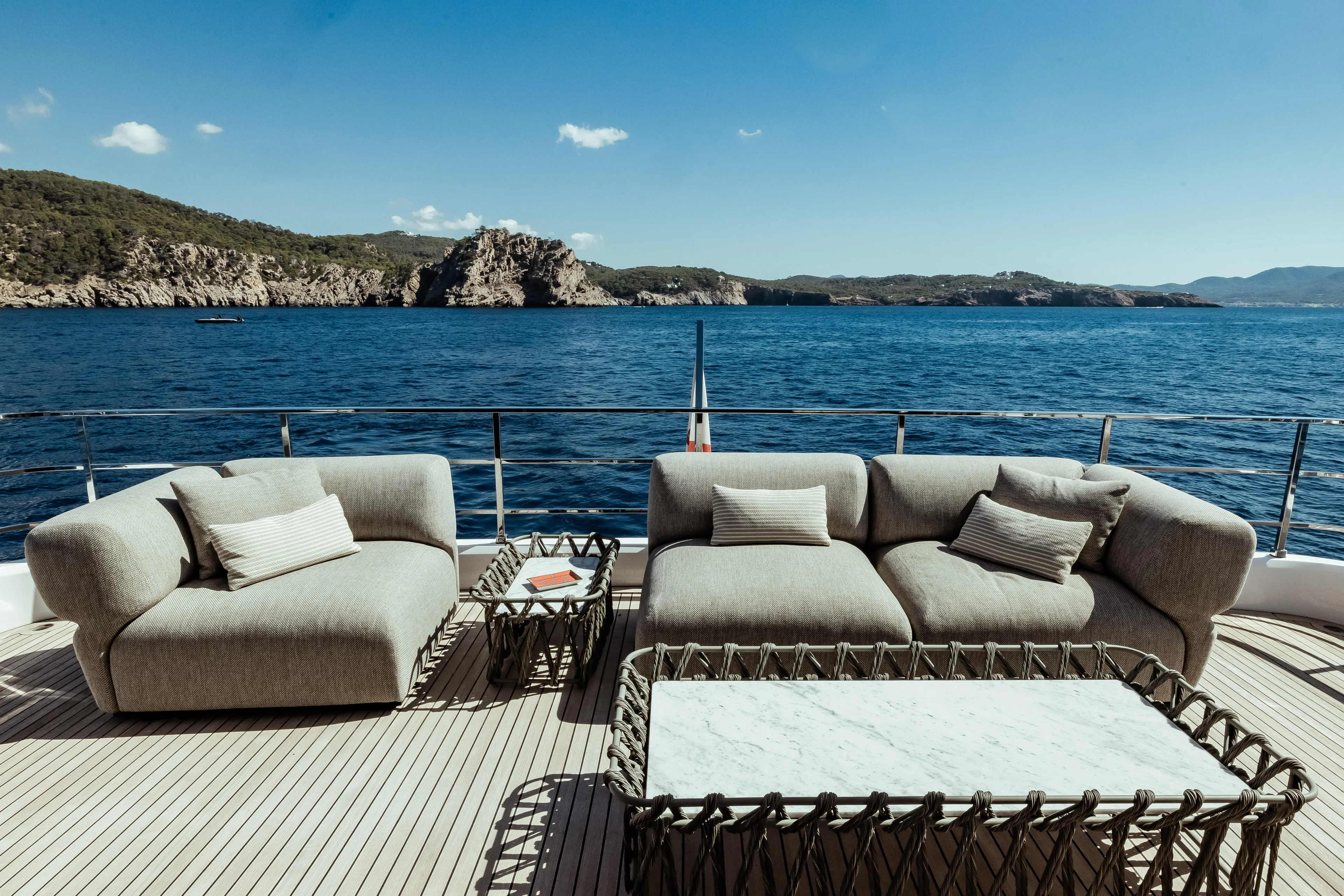  Yacht Photos Pics Luxurious outdoor seating on 2022 Custom Line Navetta 30 yacht, overlooking serene ocean and rocky coastline.