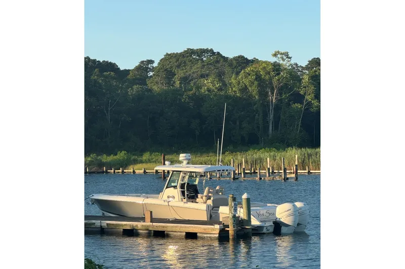  Yacht Photos Pics 2018 Boston Whaler 330 Outrage docked by a serene, wooded shoreline.