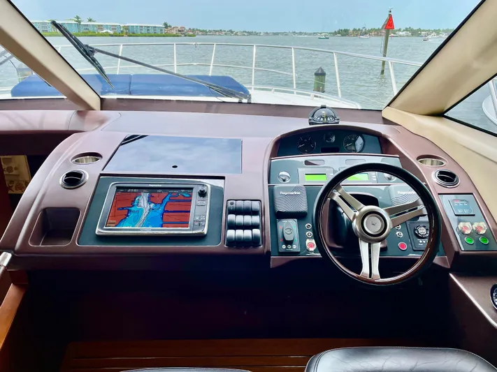  Yacht Photos Pics Helm of 2015 Princess F56 yacht with navigation system and steering wheel, overlooking calm waters.