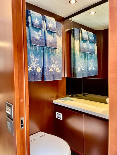  Yacht Photos Pics Luxurious yacht bathroom with wooden cabinetry, blue nautical-themed towels, and modern fixtures.