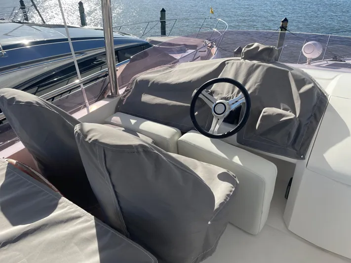  Yacht Photos Pics Steering area of a 2015 Princess f56 yacht, covered seats, overlooking water.