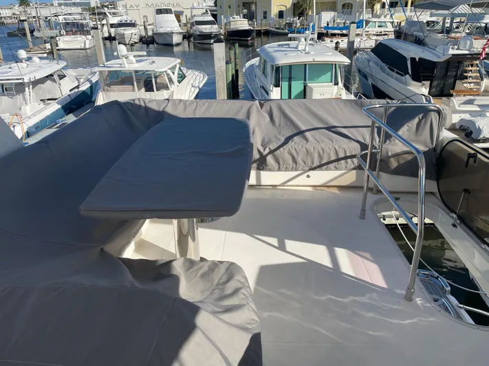  Yacht Photos Pics Flybridge of 2015 Princess f56 yacht with covered seating and table, docked at marina.