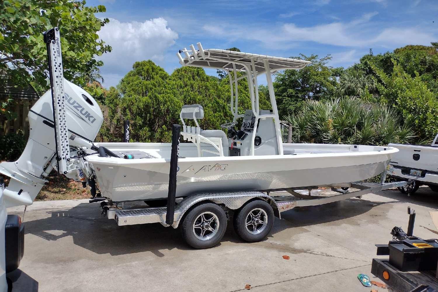 2022 Avid 23 FS Magnum boat on trailer with Suzuki outboard motor, parked outdoors.